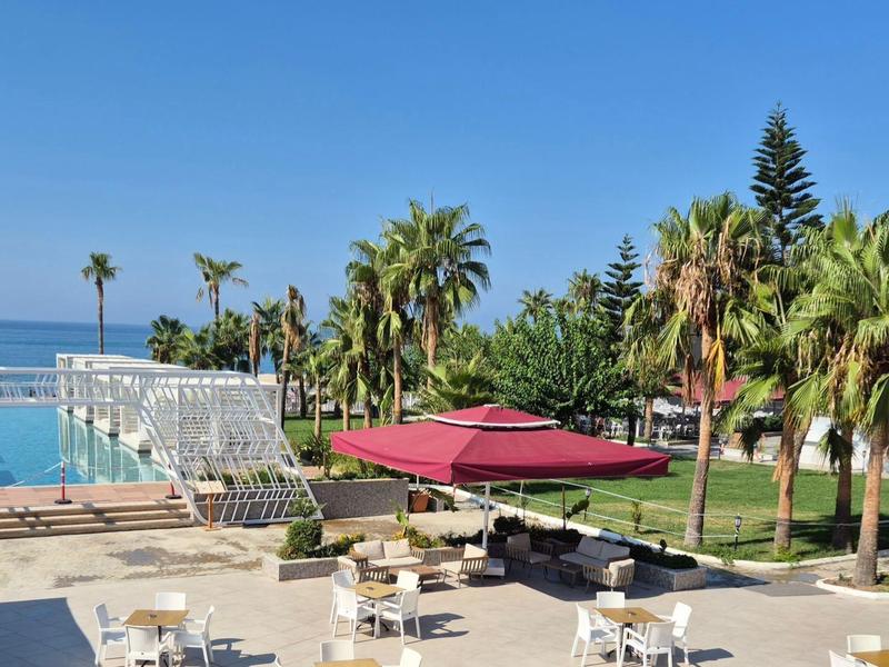 Hotelterras met tafels, parasol, palmbomen en uitzicht op zee