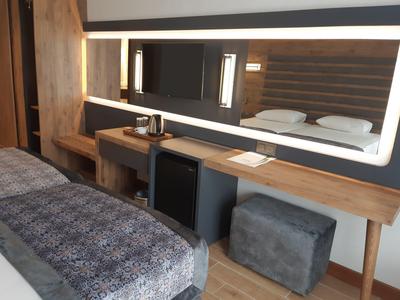 Modern hotelkamer met grote spiegel, bureau, minibar en comfortabel bed.