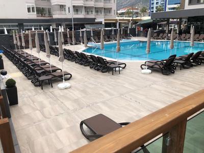 Hotelová bazénová plocha s lehátky a zavřenými slunečníky.