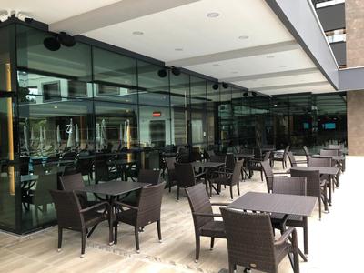 Buitenterras van een hotel met moderne glazen wanden en meerdere tafels en stoelen.