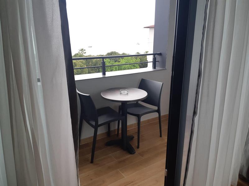 Klein balkon met ronde tafel en twee stoelen, uitzicht op groen.