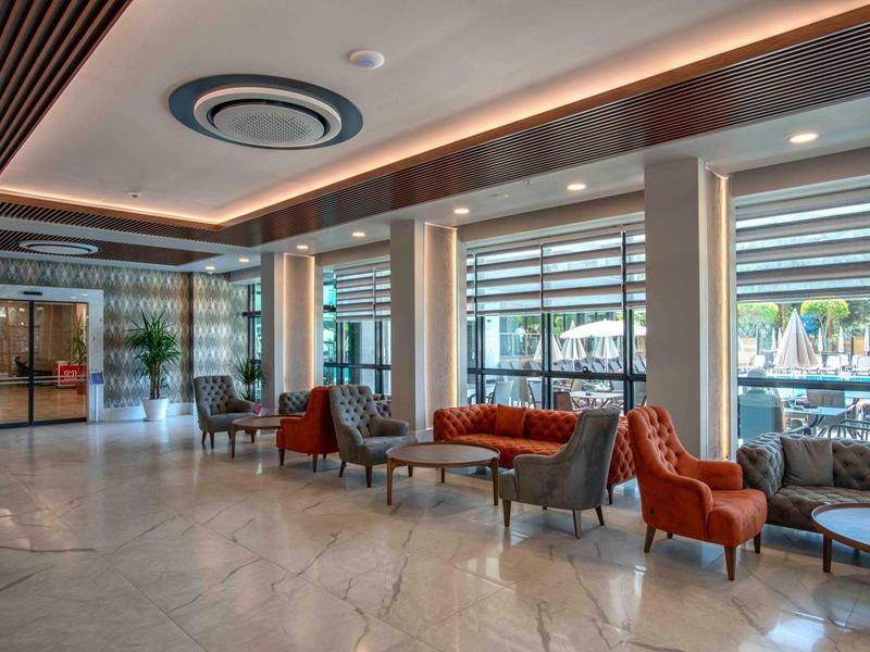 Moderne hotel lobby met fauteuils en grote ramen met uitzicht op het zwembad.