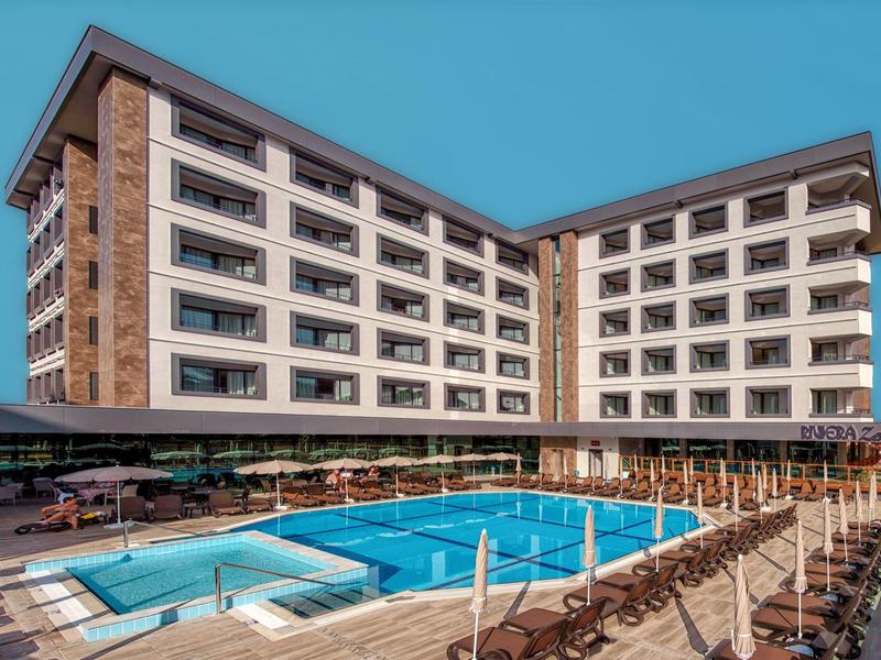 Modern hotel met groot buitenzwembad, ligstoelen en heldere lucht.