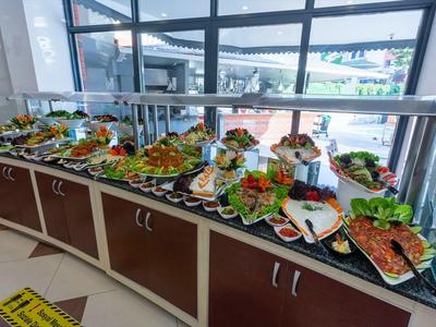 Buffet mit vielfältigen Salaten, frischem Gemüse und verschiedenen Dressings an großen Tellern.
