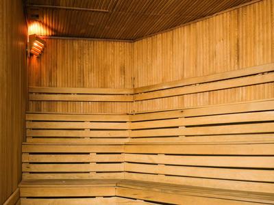 Saunaraum mit mehrstufigen, hellen Holzliegen und warmem Licht an der Wand.