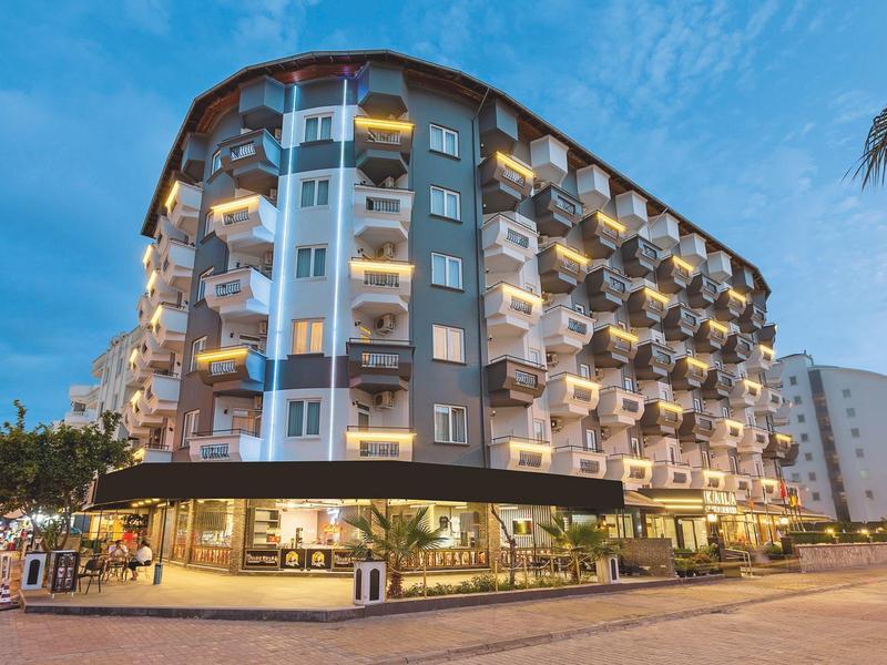 Bâtiment d'hôtel moderne avec balcons éclairés et palmiers au crépuscule