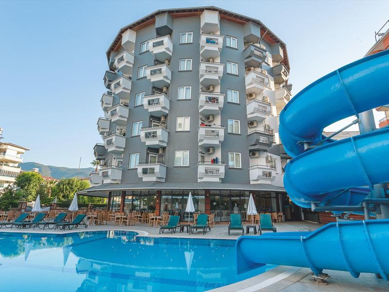 Bâtiment d'hôtel rond avec balcons et toboggan bleu à côté d'une piscine.