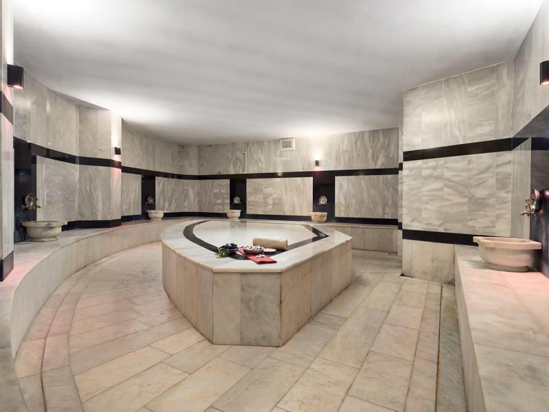 Salle de spa avec bain à remous central et revêtement en pierre claire.