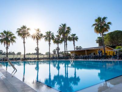 Vista di una piscina dell'hotel con palme e luce solare nelle prime ore del mattino.