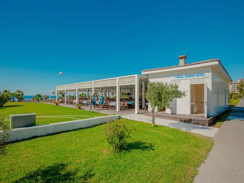 Éénlaagse hotel met zitplaatsen buiten en groen gazon onder een heldere blauwe hemel