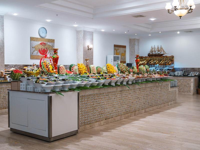 Buffettafel met fruit en desserts in een lichte, ruime eetzaal.