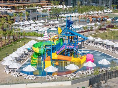 Bunter Wasserpark mit Rutschen und Liegestühlen an einem Hotelpool im Freien.