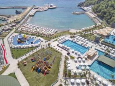 Blick auf eine Küstenanlage mit Wasserpark, Pools, Wegen und bewaldeten Hügeln im Hintergrund.