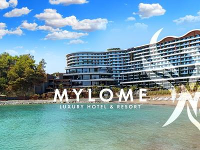 Resort moderno frente al mar con abundante vegetación y agua clara bajo un cielo azul.
