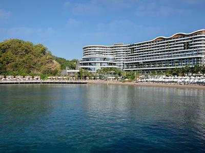Modernes Hotelgebäude am Wasser mit umliegenden Bäumen und klarem Himmel.