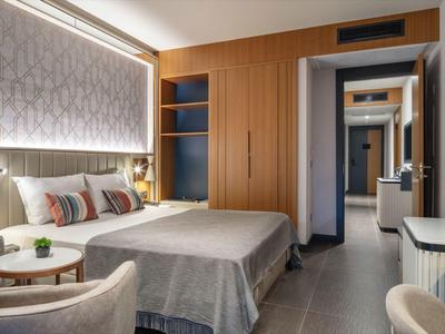 Modern eingerichtetes Hotelzimmer mit Doppelbett, Sitzbereich und schlichter Farbkombination.
