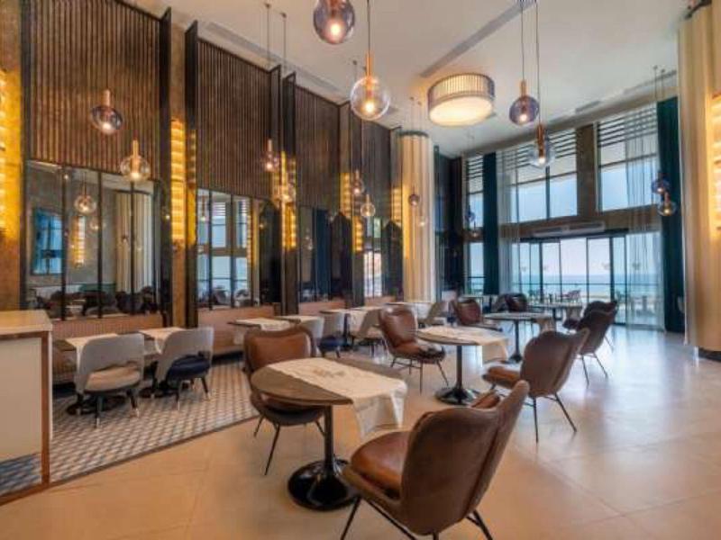 Modernes Wohnzimmer mit braunen Sesseln, großen Fenstern und hängenden Kugel-Lampen.