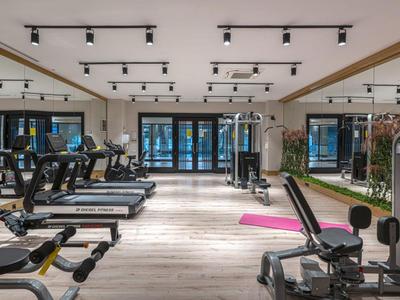 Palestra moderna con tapis roulant, macchine per esercizi di forza e grandi finestre.