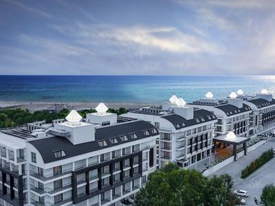 Widok z lotu ptaka na nowoczesny hotel blisko morza pod częściowo pochmurnym niebem.