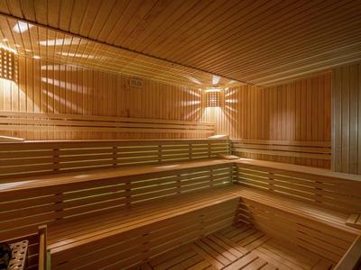 Wnętrze sauny z drewna z wielopoziomowymi ławkami i ciepłym oświetleniem.
