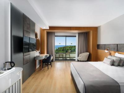 Camera d'hotel moderna con letto king-size e balcone con vista mare