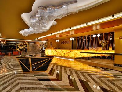 Nowoczesne wnętrze hotelowego lobby z złotą recepcją i geometryczną marmurową podłogą.