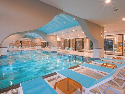 Wnętrze z basenem i niebieskimi leżakami w hotelu