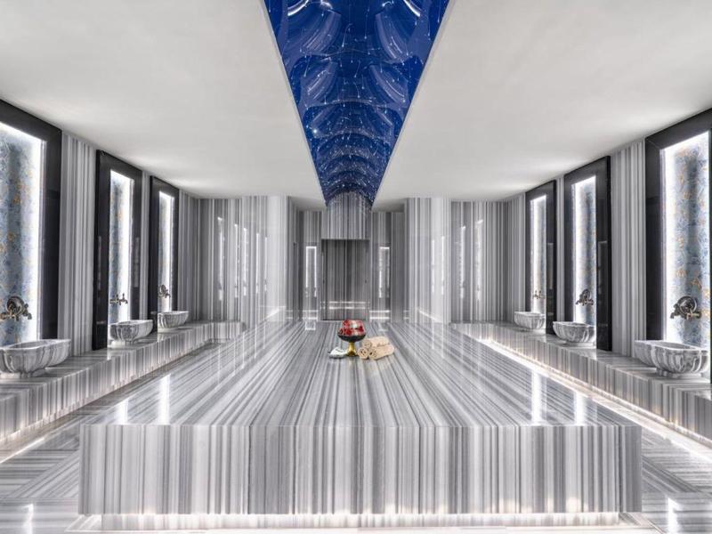 Luksusowe wnętrze z długim centralnym basenem pod niebieskim zdobionym sufitem.