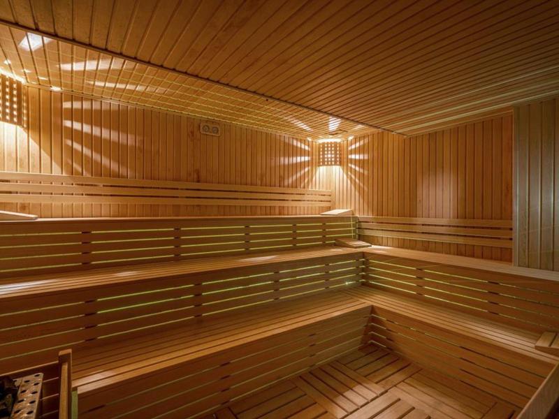 Wnętrze sauny z drewna z wielopoziomowymi ławkami i ciepłym oświetleniem.