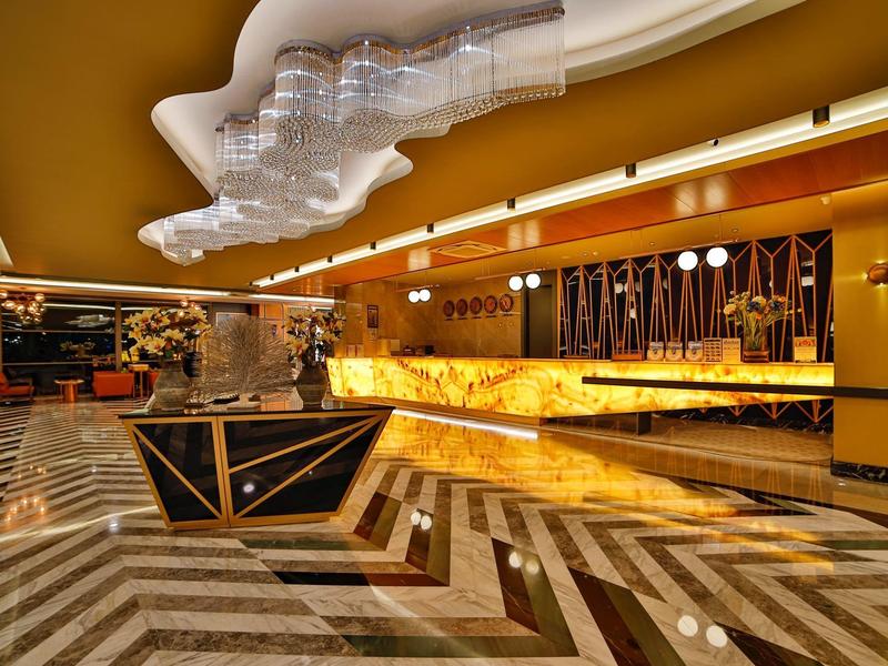 Nowoczesne wnętrze hotelowego lobby z złotą recepcją i geometryczną marmurową podłogą.