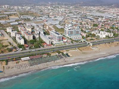 Veduta aerea di una spiaggia con promenade e città sullo sfondo sul Mar Mediterraneo.