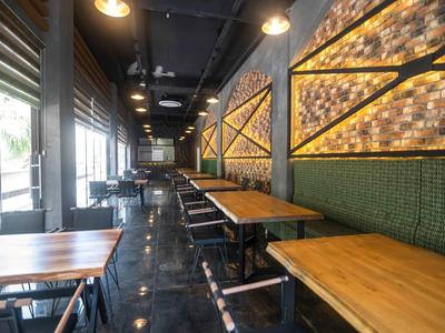 Restaurante moderno del hotel con mesas de madera, bancos verdes y pared iluminada cálidamente.