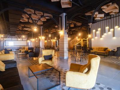 Área acogedora de la recepción del hotel con sillones cómodos, sofás y ambiente de luz cálida.