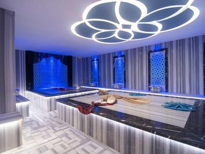 Área de spa moderna con luz de techo iluminada y varias piscinas en tonos fríos azul y gris.