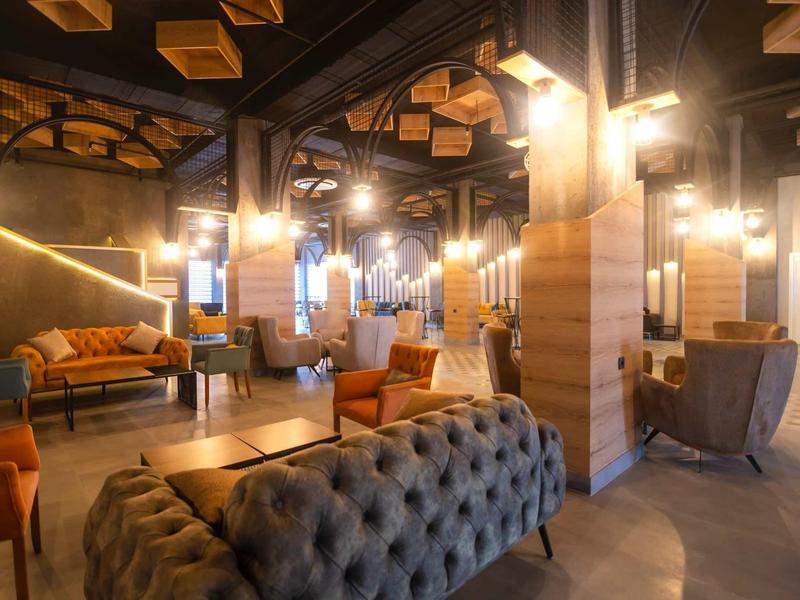 Área de lounge acogedora en hotel con sofás, sillones y luz cálida en diseño moderno.