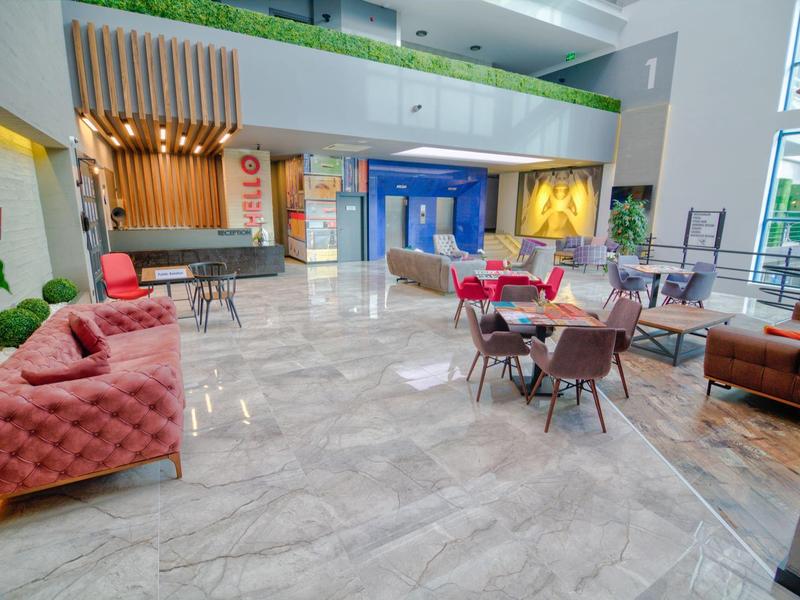 Ruim moderne hotel lobby met comfortabele banken en tafels op marmeren tegelvloer.