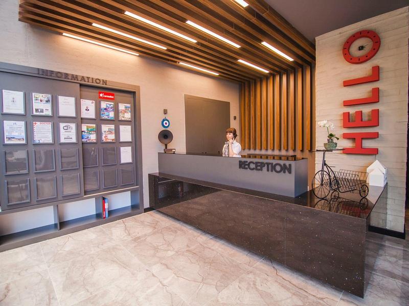 Moderne hotelreceptie met balie, brievenbussen en decoratief HELLO-bord aan de muur.