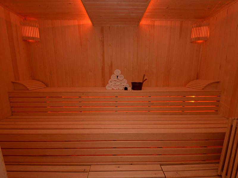 Interieur van een klassieke sauna met houten banken en warm gloeiend licht.