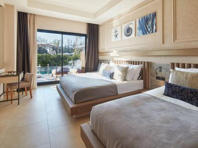 Camera d'hotel moderna con due letti e grande finestra con vista su una terrazza.