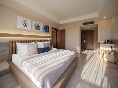 Camera d'hotel moderna con grande letto, pavimento in legno chiaro e decorazioni murali.