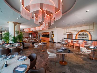 Moderní hotelová restaurace s elegantním kruhovým stropním osvětlením a útulnými posezeními.