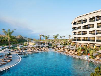 Moderní hotelový bazén s lehátky a palmami pod modrou oblohou.