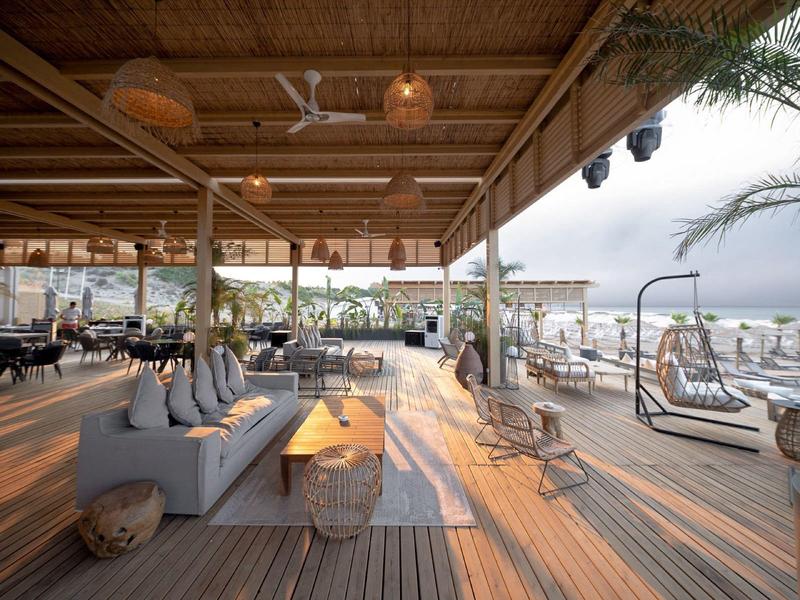 Area lounge aperta dell'hotel con arredamento moderno, posti a sedere e vista sulla spiaggia.