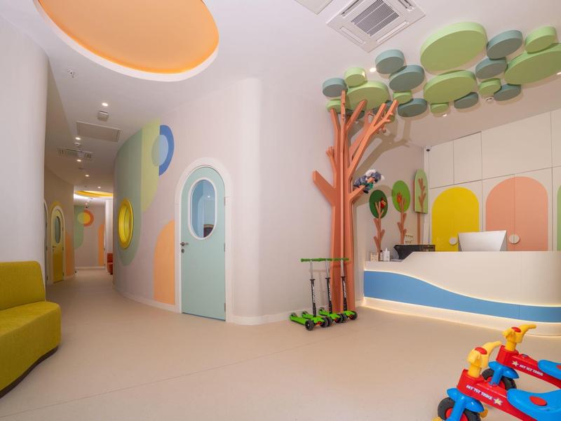 Area gioco moderna e colorata in un hotel con zona salotto e decorazioni murali adatte ai bambini.