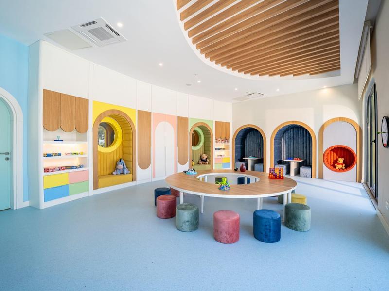 Chambre d'enfants moderne et colorée avec aire de jeux et tabourets dans un hôtel ou une structure pour enfants.