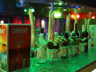 Barevný bar s řadami sklenic a osvětlenými nabídkami nápojů