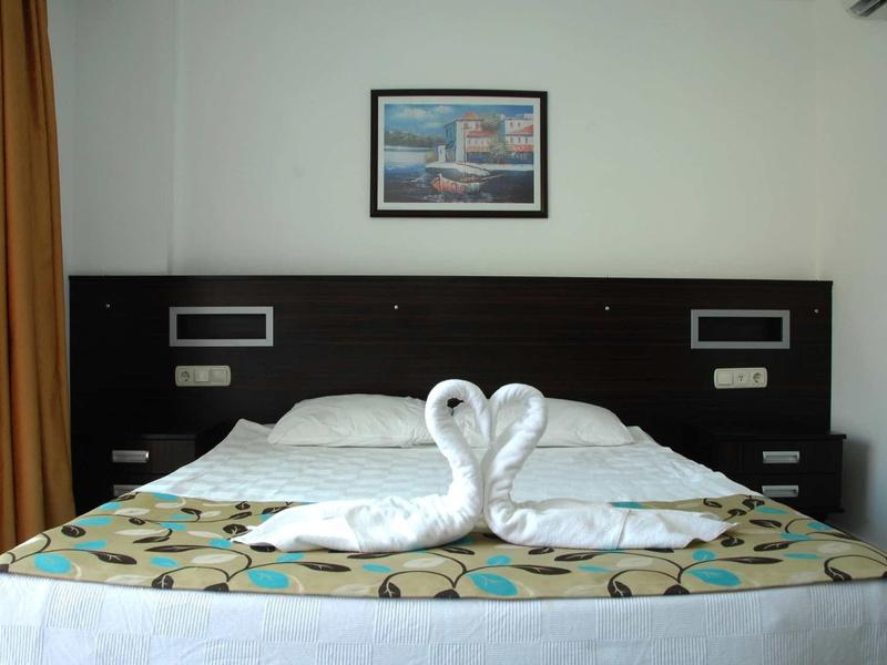 Ein schlichtes Schlafzimmer mit Doppelbett, zwei Schwänen aus Handtüchern und einem Bild an der Wand.