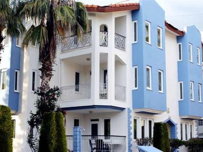 Edificio dell'hotel azzurro chiaro con balconi bianchi e palme in primo piano in una giornata di sole