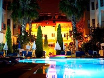 Piscina esterna illuminata di notte con edifici e palme circostanti