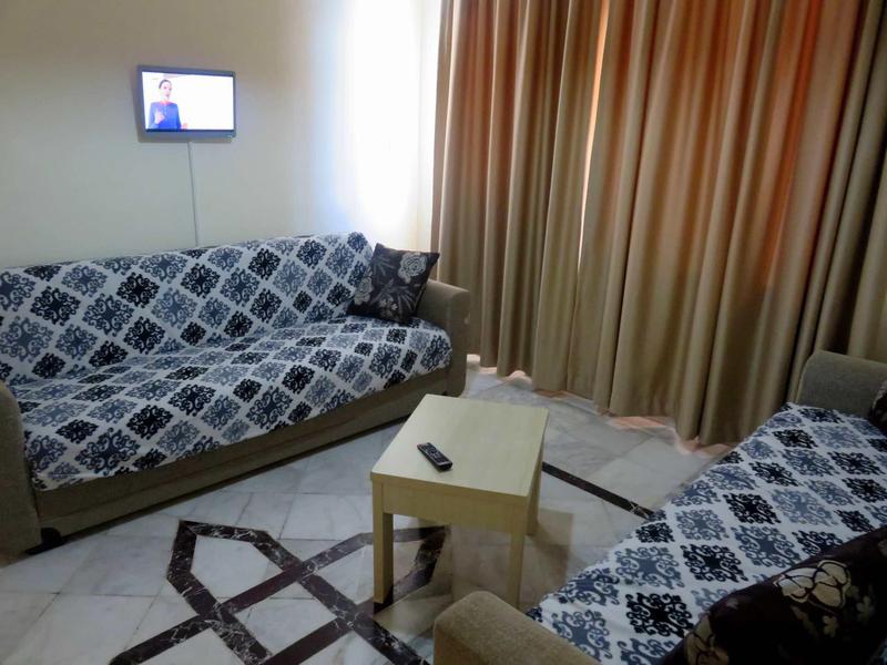 Przytulny salon z dwiema sofami, małym stolikiem i zasłoniętymi zasłonami.